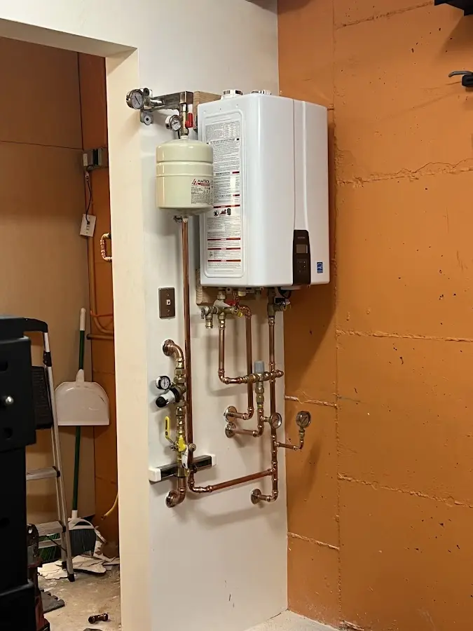 Plumbing technician inspecting water heater connections in Gering